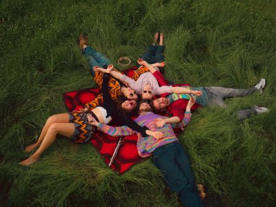 Die fünf Mitglieder von The Citadel liegen in Sternform auf einer rot-gemusterten Picknickdecke im Gras