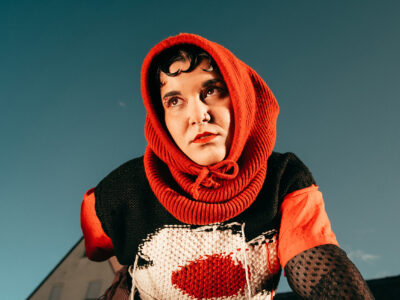LNA in einem roten Strickoutfit, fotografiert von unten.