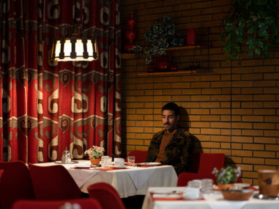 Der Rapper sitzt alleine in einem großen Restaurant.